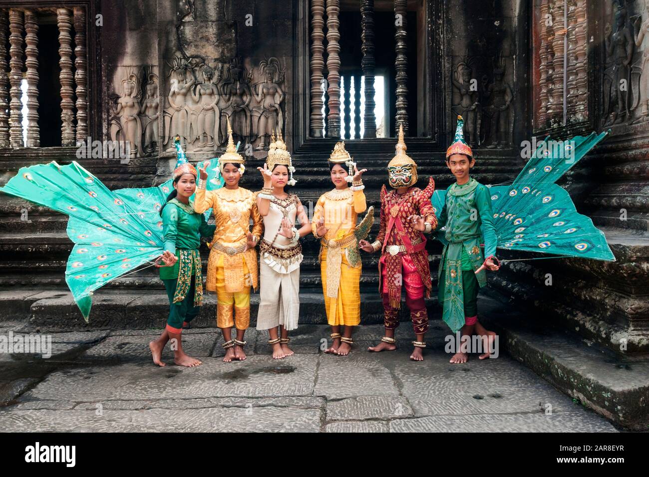 Traditional Apsara Dancers in colorful costumes with striking fans pose in front of Angkor Wat ruins, Siem Reap, Cambodia Stock Photo
