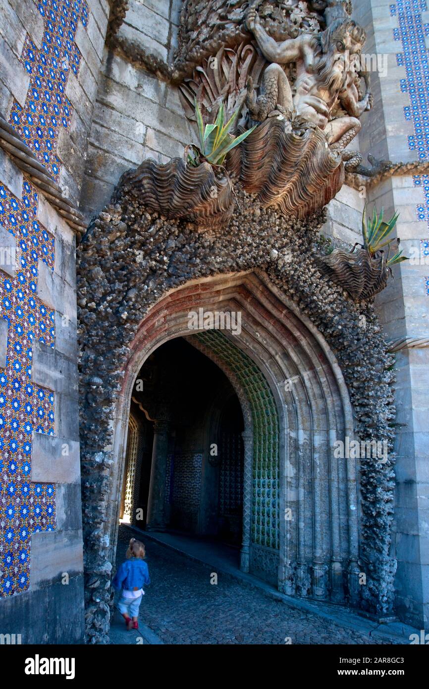 A child wanders into the entrance under the watchful gaze of the stone monster guarding the entrance to Pena Palace, built in a combination of Gothic, Stock Photo
