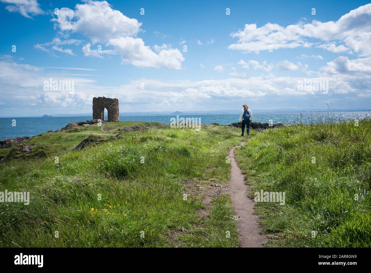 Tourist on the hiking path leading to the unusual stone Lady Tower built in the 1760's perched on the North Sea, East Neuk of Fife, Elie, Scotland, UK Stock Photo