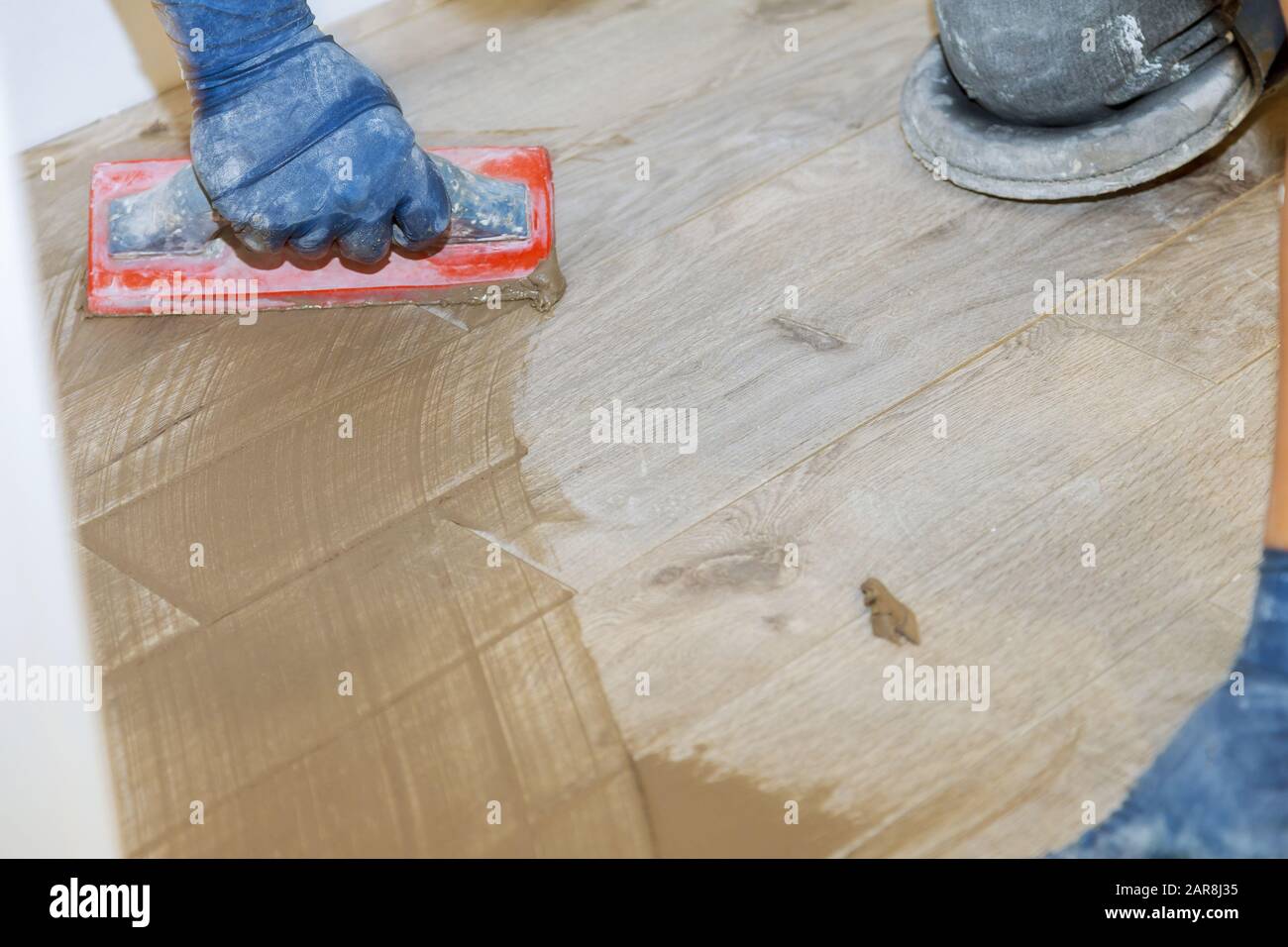 Builder applying grouting on shower tiles in bathroom gray cement