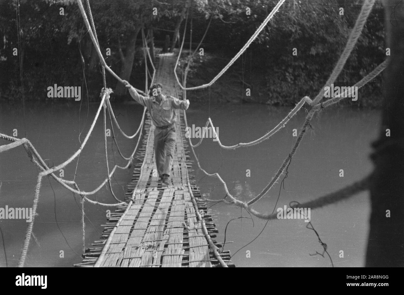 Shock troops at Praboemoelih  Talang Djimar (at Prabuumelih): Reverend Berhof from Roden, the field preacher of 7 R.S., does balancing exercises on the Wilhelmina Bridge about the Ajer Rambangs at Prabamoelih. This bridge was constructed from bamboo by infantrymen of 1-7 R.S. and opened on 31 August. Date: 23 October 1947 Location: Indonesia, Dutch East Indies Stock Photo