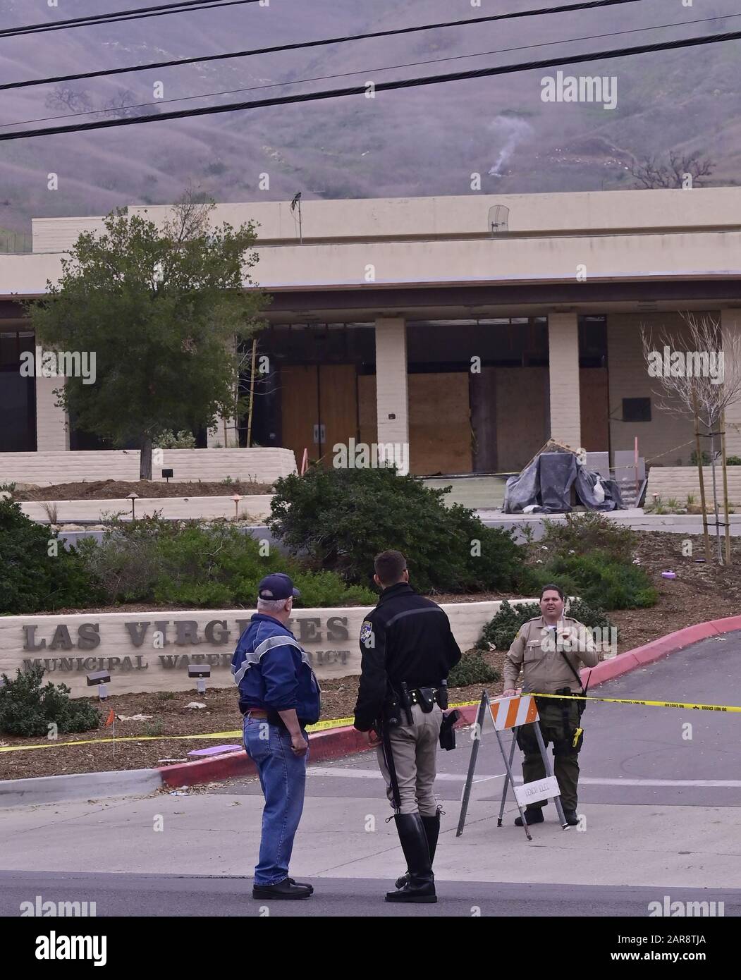 File Calabasas United States 26th Jan Law Enforcement Officers Stand On The Street Near The Scene Where Firefighters Work To Contain Smoldering Wreckage Of A Helicopter Crash That Claimed The Life