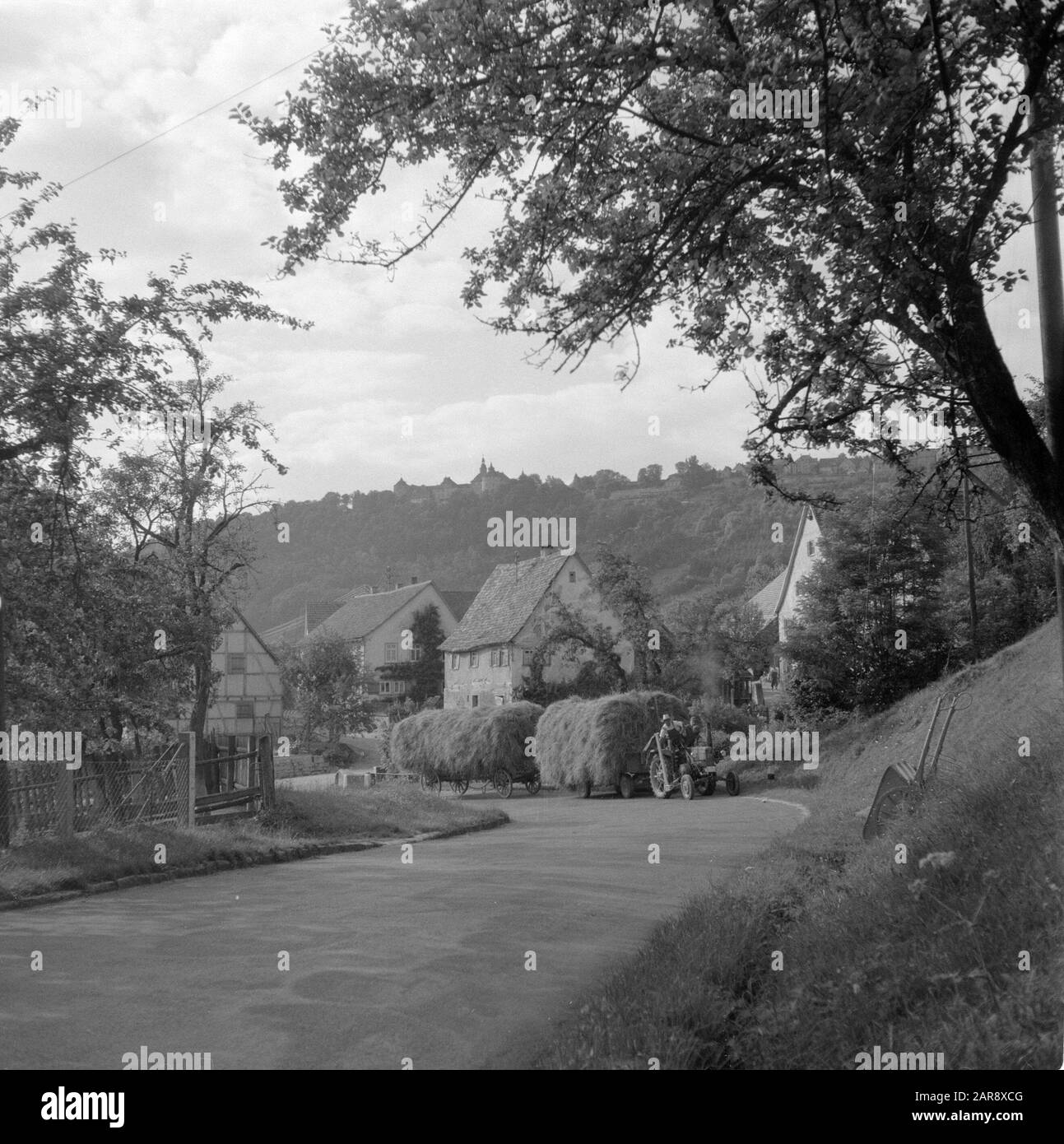 Hohenloher Land  Tractor with wagons hay in Bächlingen, on the hill Castle Langenburg Date: 1954 Location: Baden-Württemberg, Bächlingen, Germany, West Germany Keywords: village images, hay, castles, agriculture, tractors Stock Photo