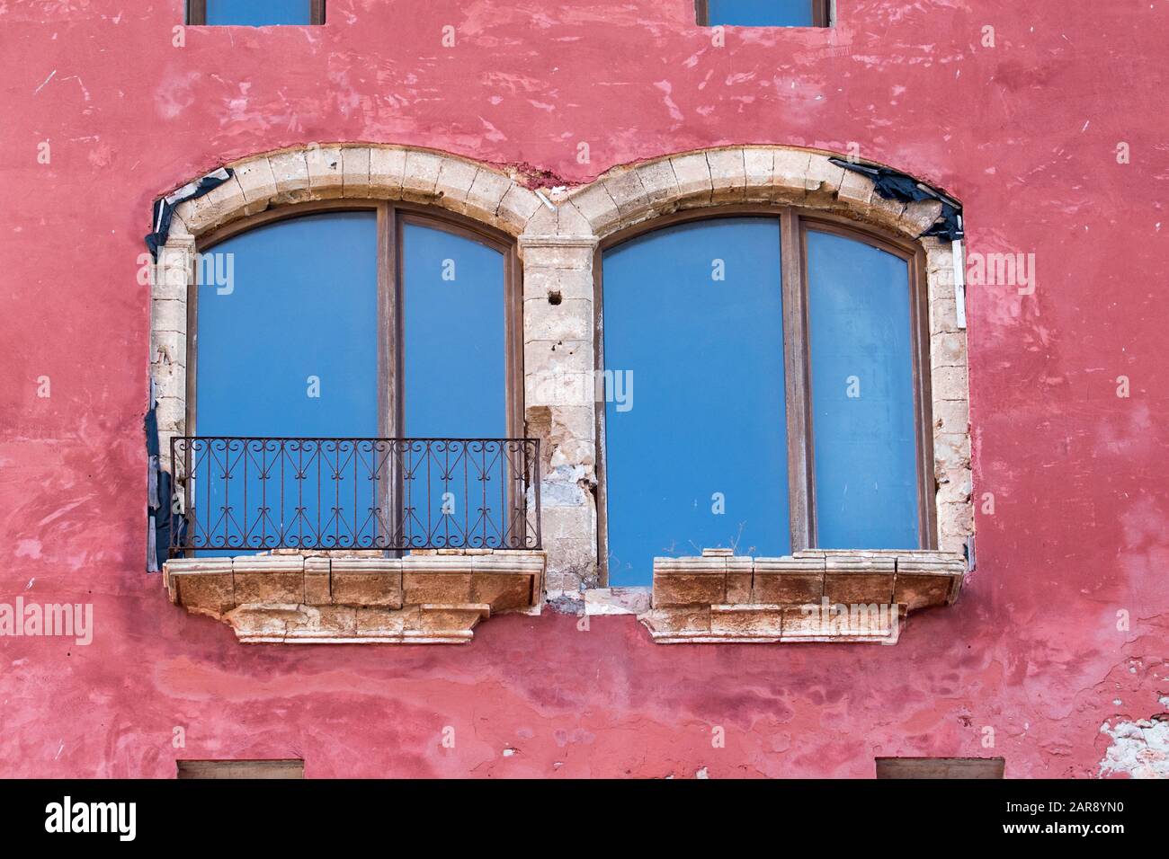 Large arched balcony windows on a red wall of a building on the top of Eivissa (Ibiza Town), Ibiza, Balearic Islands Stock Photo