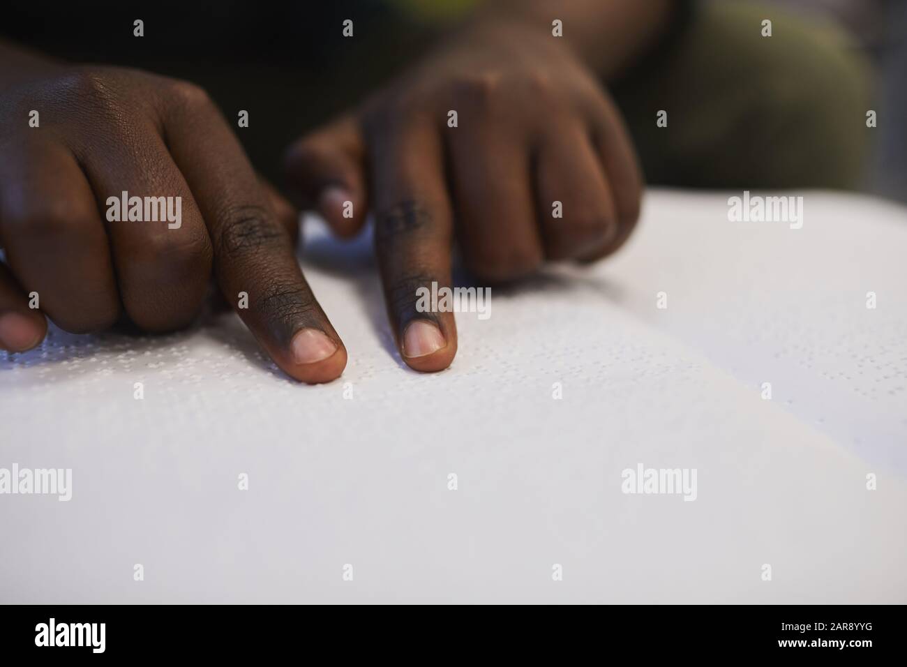 Closeup of unrecognizable blind African man reading braille book while studying in school, copy space Stock Photo
