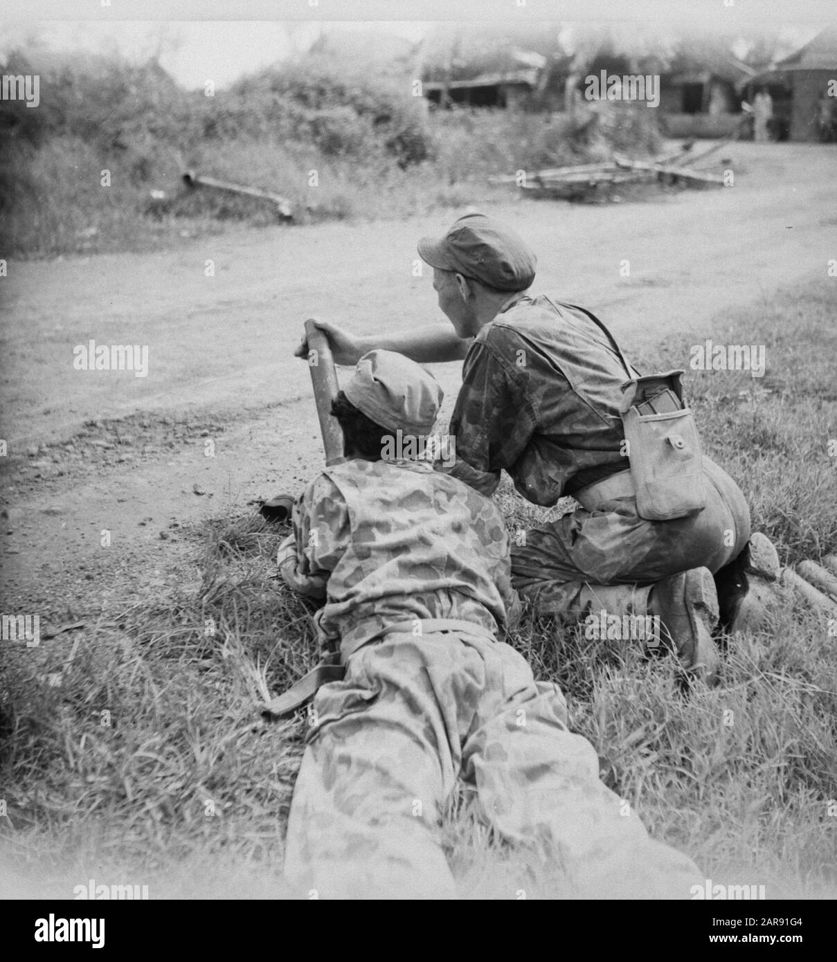Two soldiers with a light mortar in position along the road Annotation: DJKNIET IN order Date: 1947 Location: Indonesia, Dutch East Indies Stock Photo