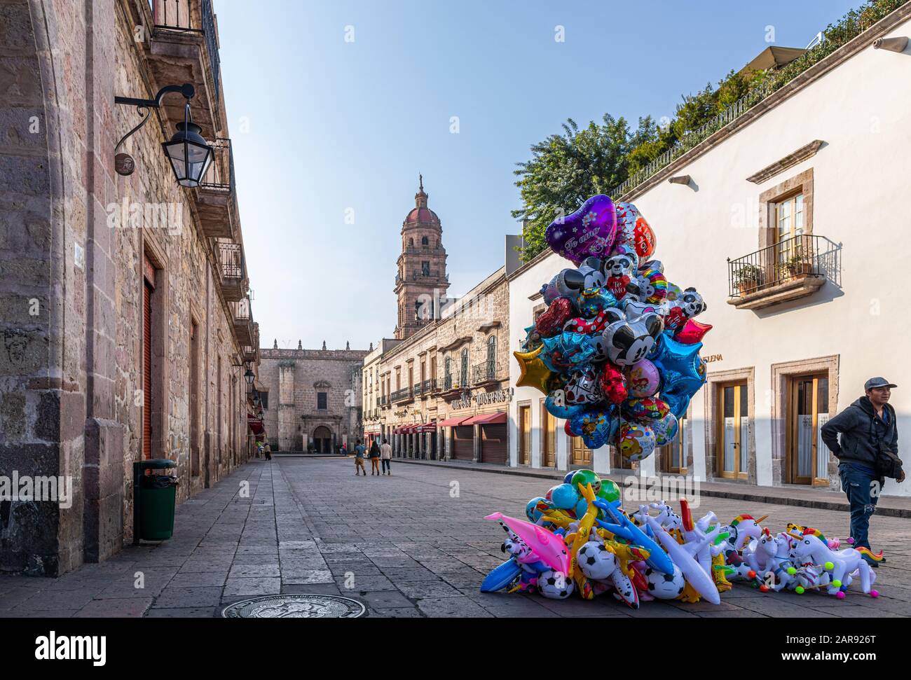 Morelia, Michoacan, Mexico - November 24, 2019: View down Hidalgo street, with a balloon vendor and the San Agustin temple on the background Stock Photo