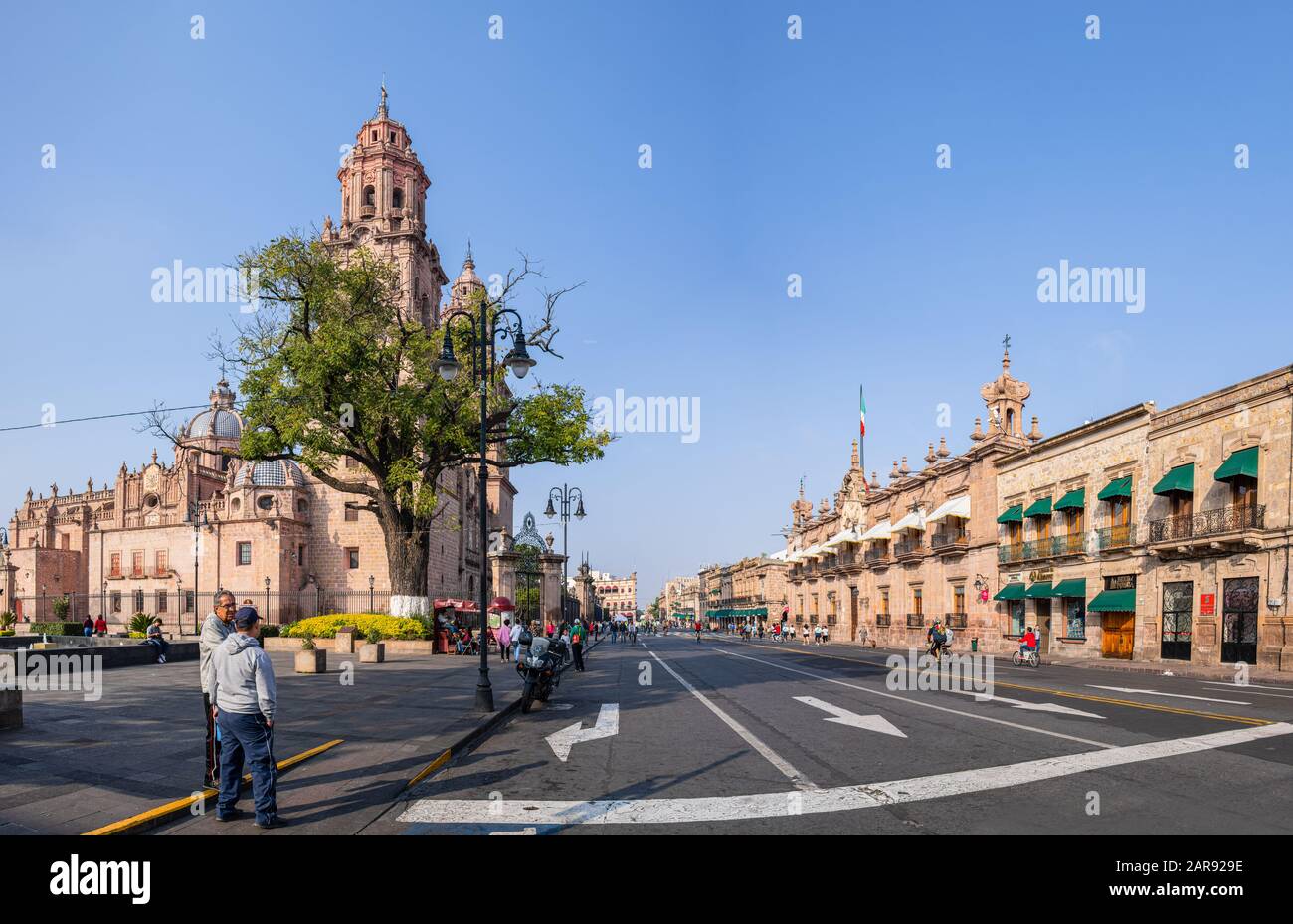 Morelia, Michoacan, Mexico - November 24, 2019: The Morelia Cathedral as seen from Mexico 15, and the Government Palace, people running and riding bik Stock Photo