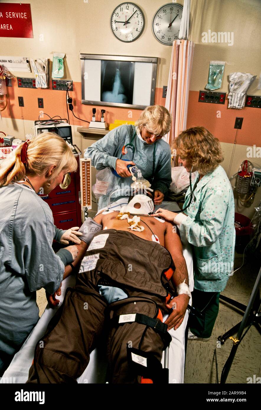 An emergency room trauma team treats an African American patient at a hospital in Mission Viejo, CA. Note X-ray in background. Stock Photo