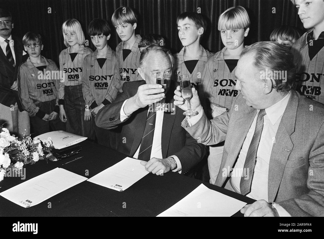 Sponsorcontract signed Sony-KNVB  Chairman of the KNVB Van Marle (l) and Mr. A. (Ton) Brandsteder of Sony (r) raise the glass; behind them stand young people Date: November 14, 1983 Keywords: youth, agreements, sponsorship, football, chairmen Personal name: Brandsteder, A., Marle, J.W. of, Marle, Jo of Institution Name: Sony Stock Photo