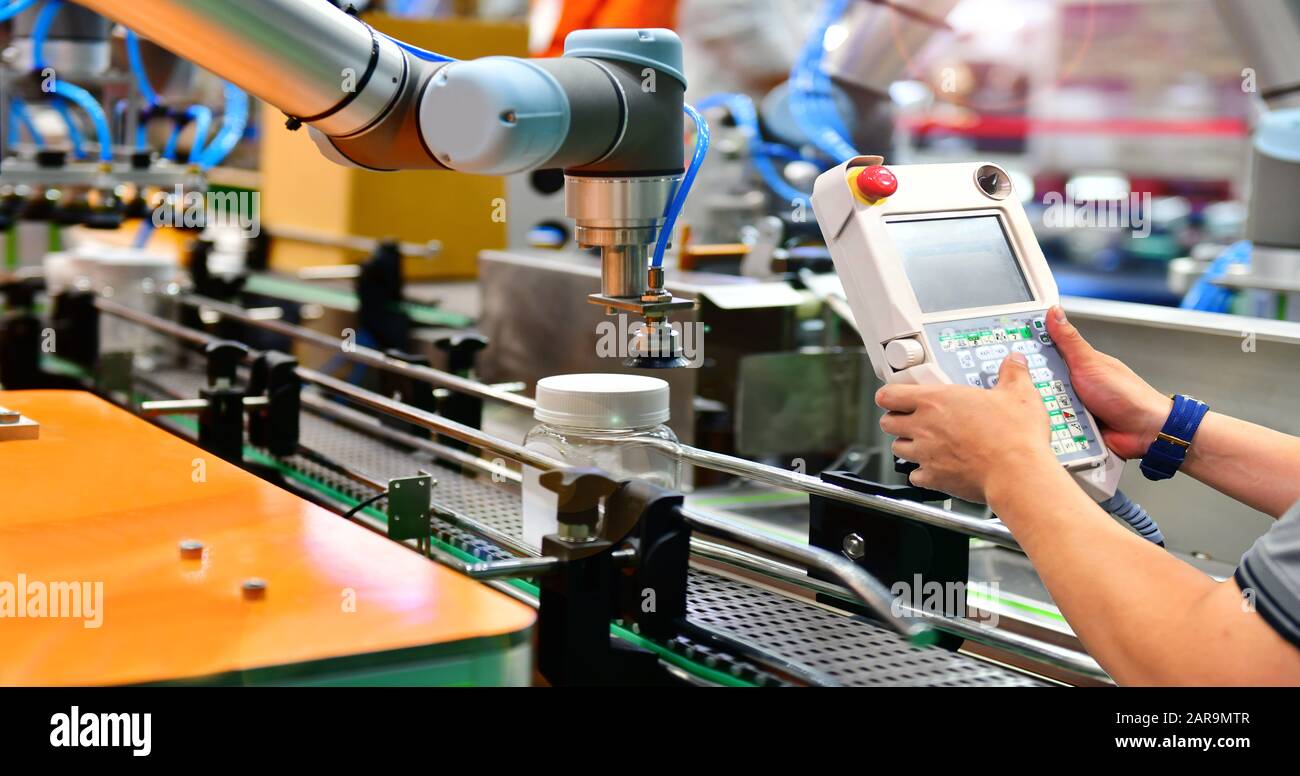 Engineer check and control automation robot arms arranged glass water bottle on Automatic industrial machinery equipment in production line factory Stock Photo