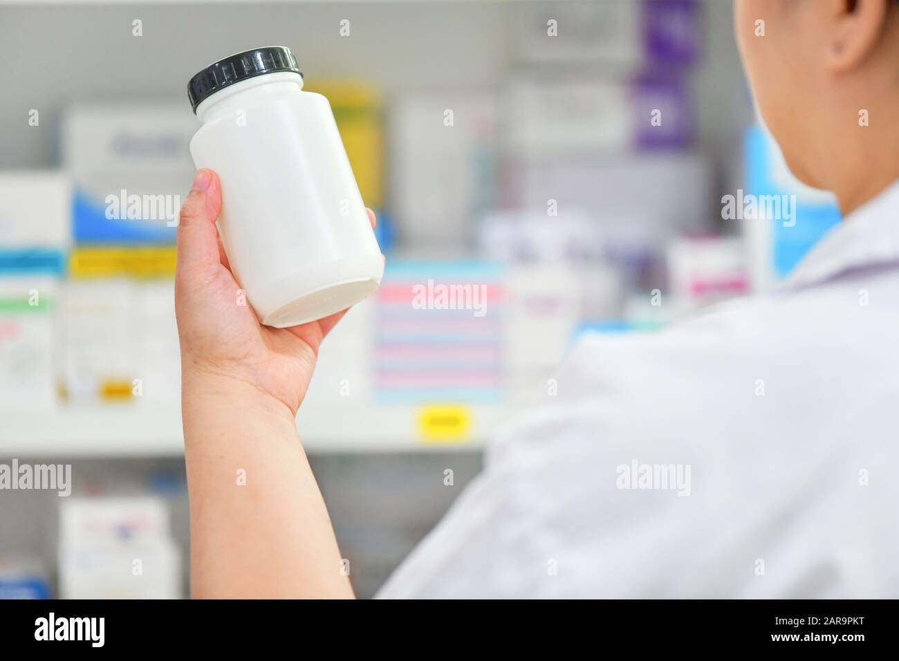 Pharmacist holding medicine bottle at the pharmacy drugstore Stock Photo