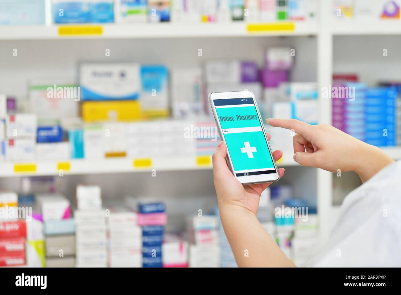 Pharmacist using mobile smart phone for search bar on display in