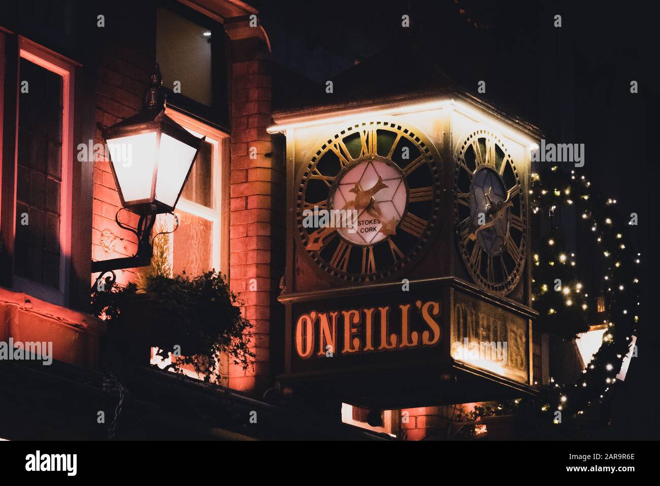 DUBLIN, IRELAND, DECEMBER 24, 2018: View of the clock on the exterior of the O'Neill's Pub and Kitchen on Suffolk Street, dimly lit and decorated for Stock Photo