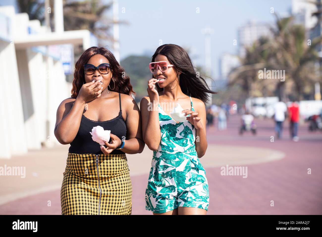 Two young women walking and eating candy floss. Stock Photo