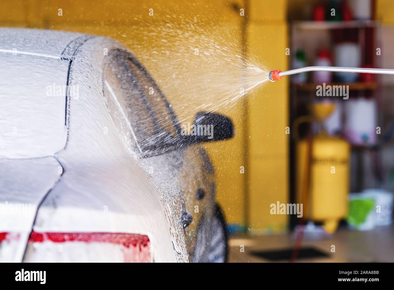 Employee washes the automobile with foam machine at the garage. Carwash concept Stock Photo