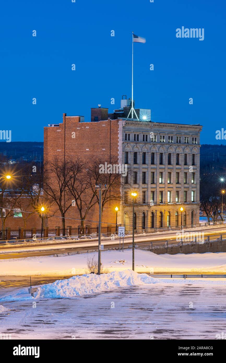 UTICA, NY - JAN 20, 2020: Closeup Aerial Night View of Downtown Utica Streets and Cars Trail Lights with Commercial Travelers Life Insurance Company B Stock Photo
