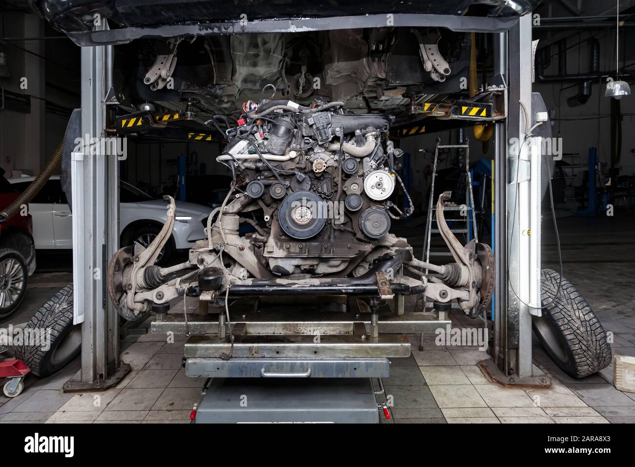 Replacement used engine on a table mounted under raised car on lift for ...