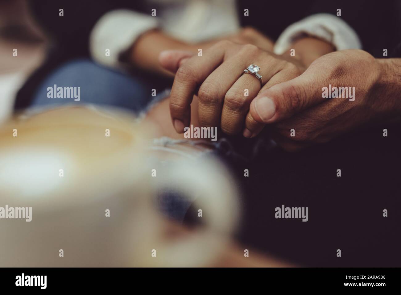 Closeup of couple holding hands at cafe together. Man holding hand