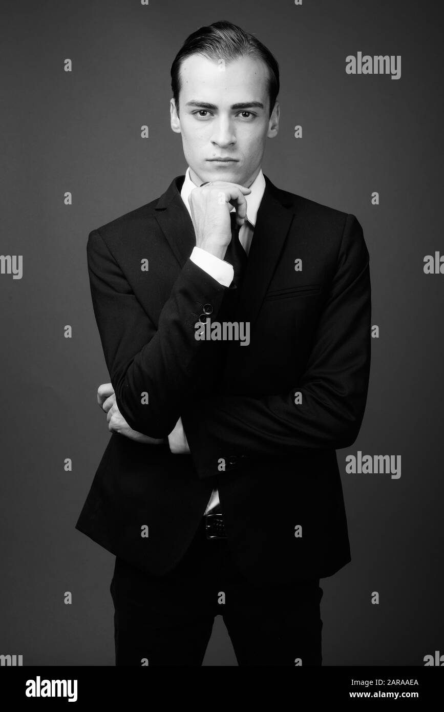 Studio shot of young businessman wearing suit against gray background