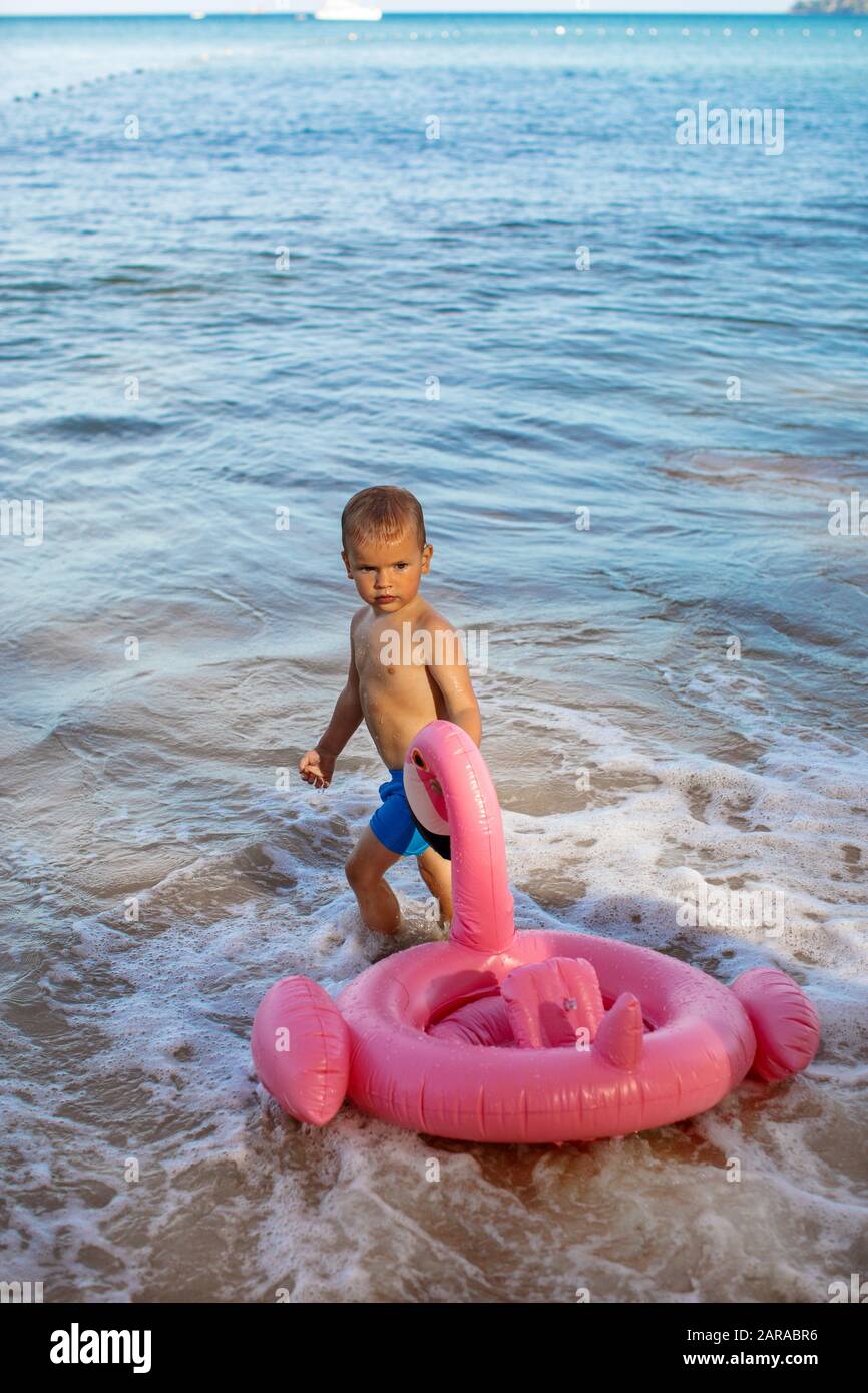 Serious kid with inflatable flamingo toy in water Stock Photo