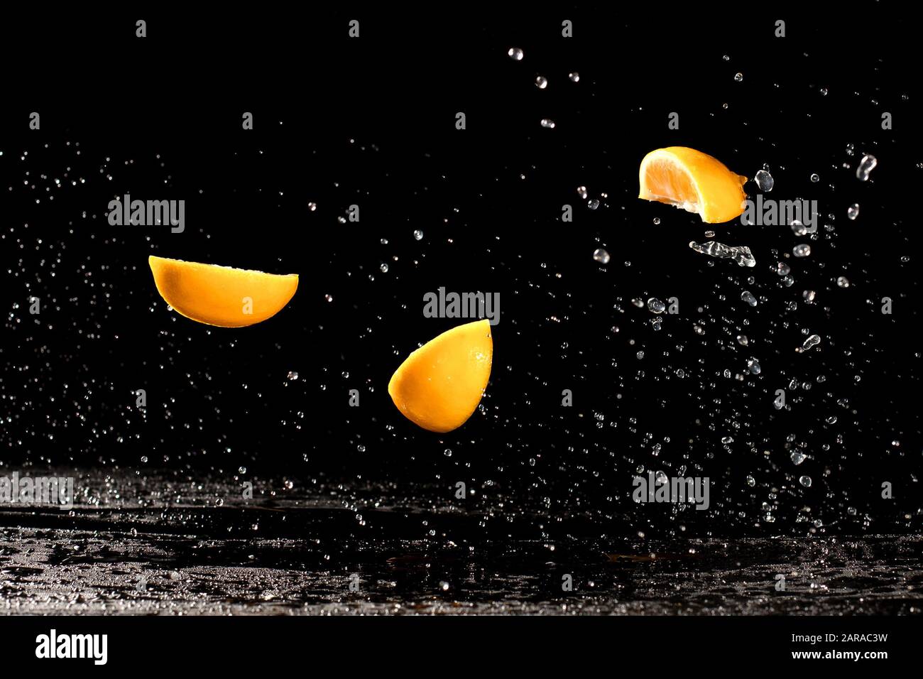 Fresh yellow lemon half in water splash on black background with lots of air bubbles. Stock Photo