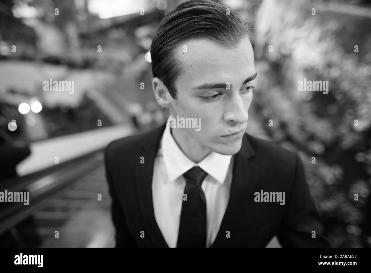 Portrait of young handsome businessman in suit exploring the city of Bangkok in black and white Stock Photo