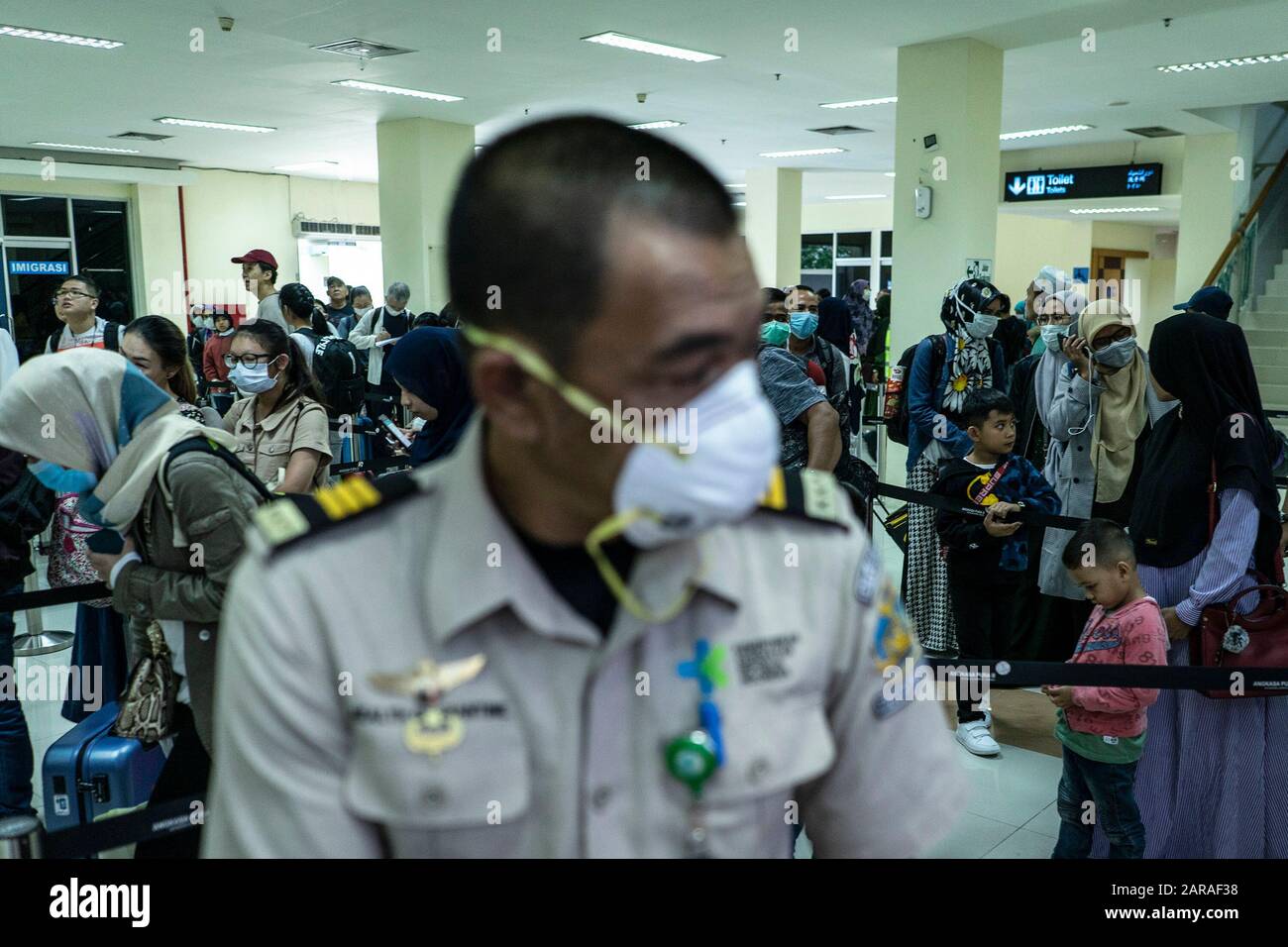Passengers wear masks on the arrival at the Sultan Iskandar Muda International Airport in Aceh Besar Regency.Indonesian government announced it was officially stopping flights to Wuhan China, a deadly new virus center, and health checks at airports in Indonesia were tightened. Stock Photo