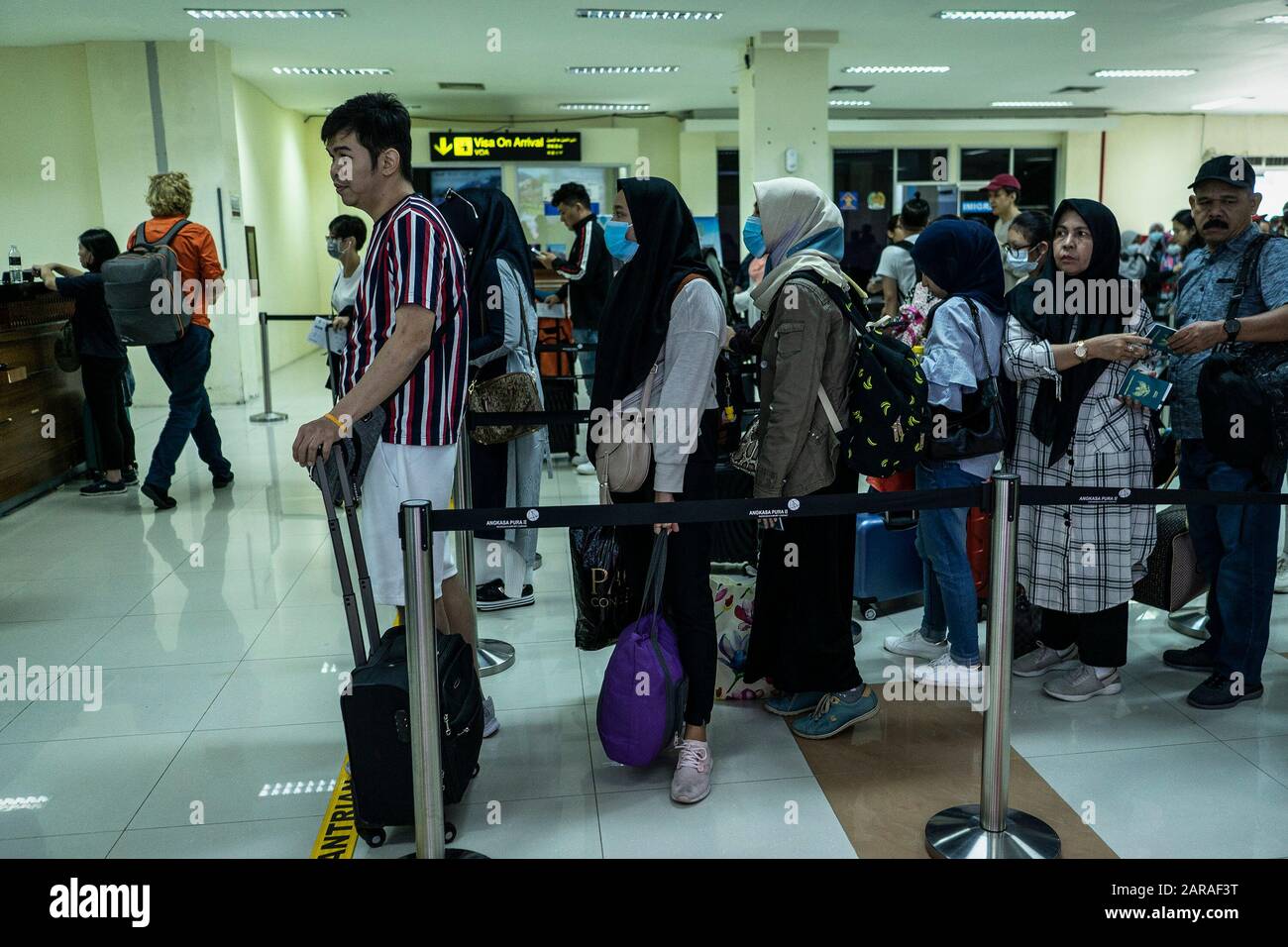 Passengers wear masks on the arrival at the Sultan Iskandar Muda International Airport in Aceh Besar Regency.Indonesian government announced it was officially stopping flights to Wuhan China, a deadly new virus center, and health checks at airports in Indonesia were tightened. Stock Photo