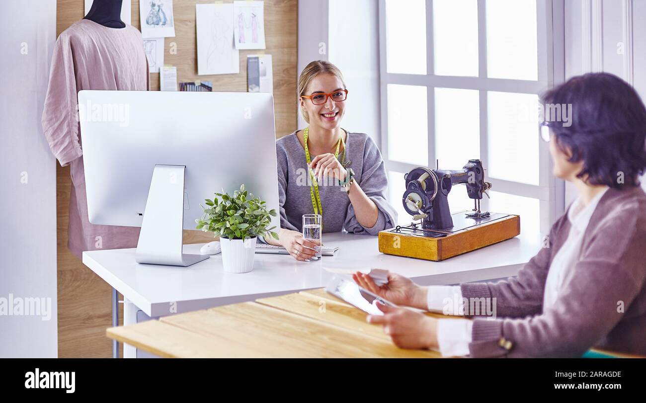 pretty dressmaker showing a new design to her client Stock Photo - Alamy