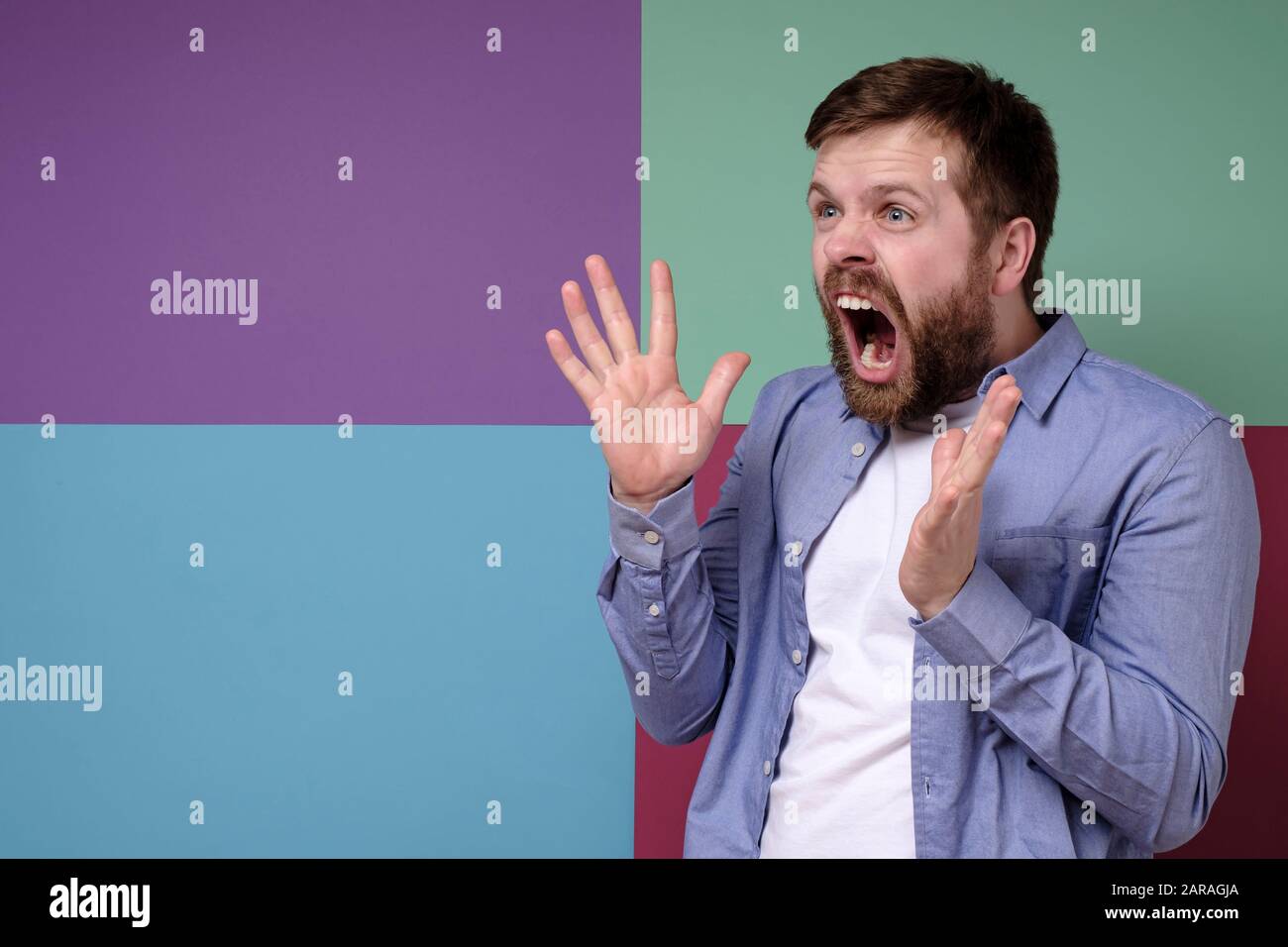 Furious, angry bearded man annoyed, he makes a gesture with hands and shouts loudly, with copy space. Stock Photo