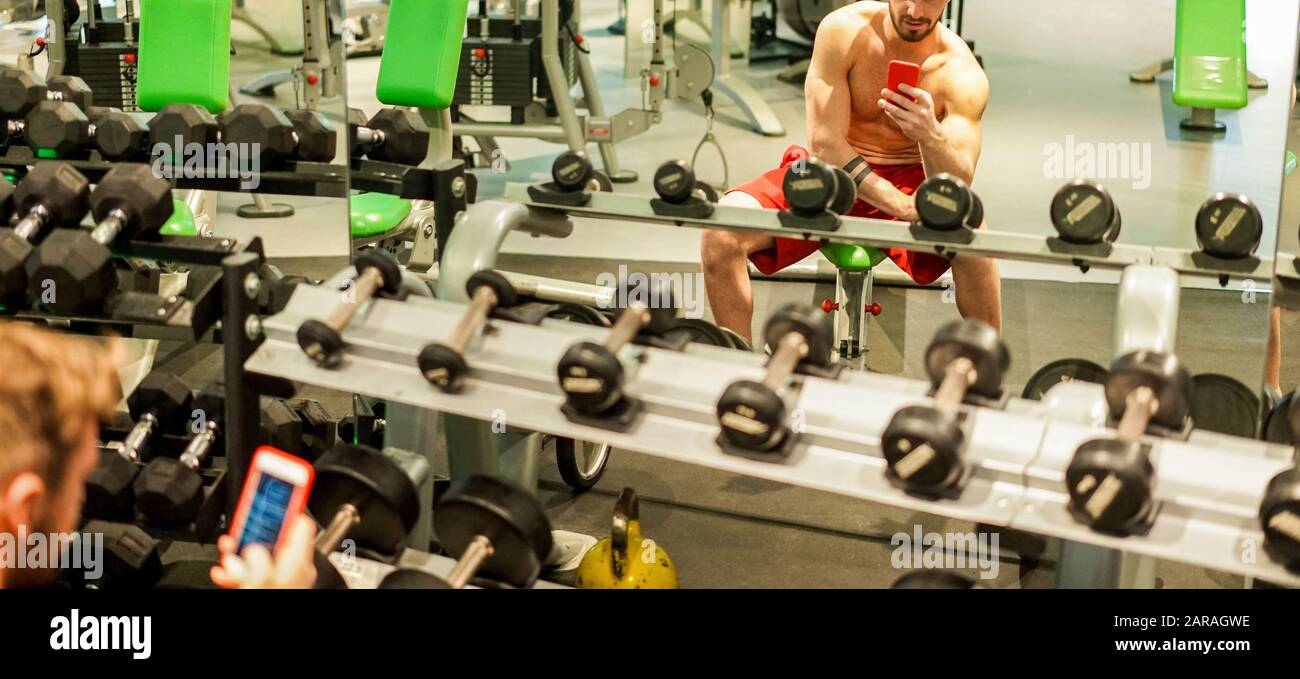 Young fitness personal trainer using mobile smartphone inside gym ...