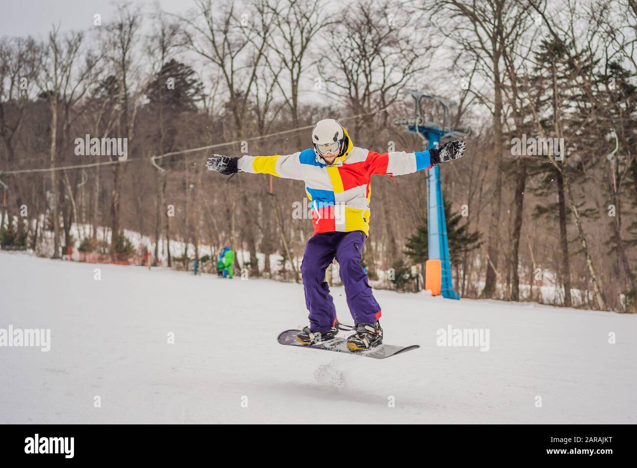 Young man jumping with a snowboard in the mountains Stock Photo