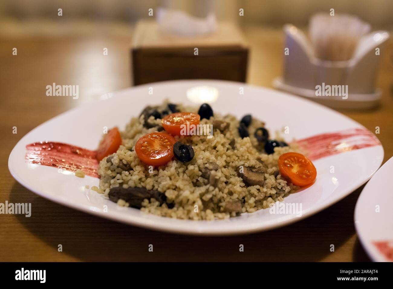 Bulgerty Eatable Bulgur with beef, cherry tomatoes and olives. Dish served in restaurant ...