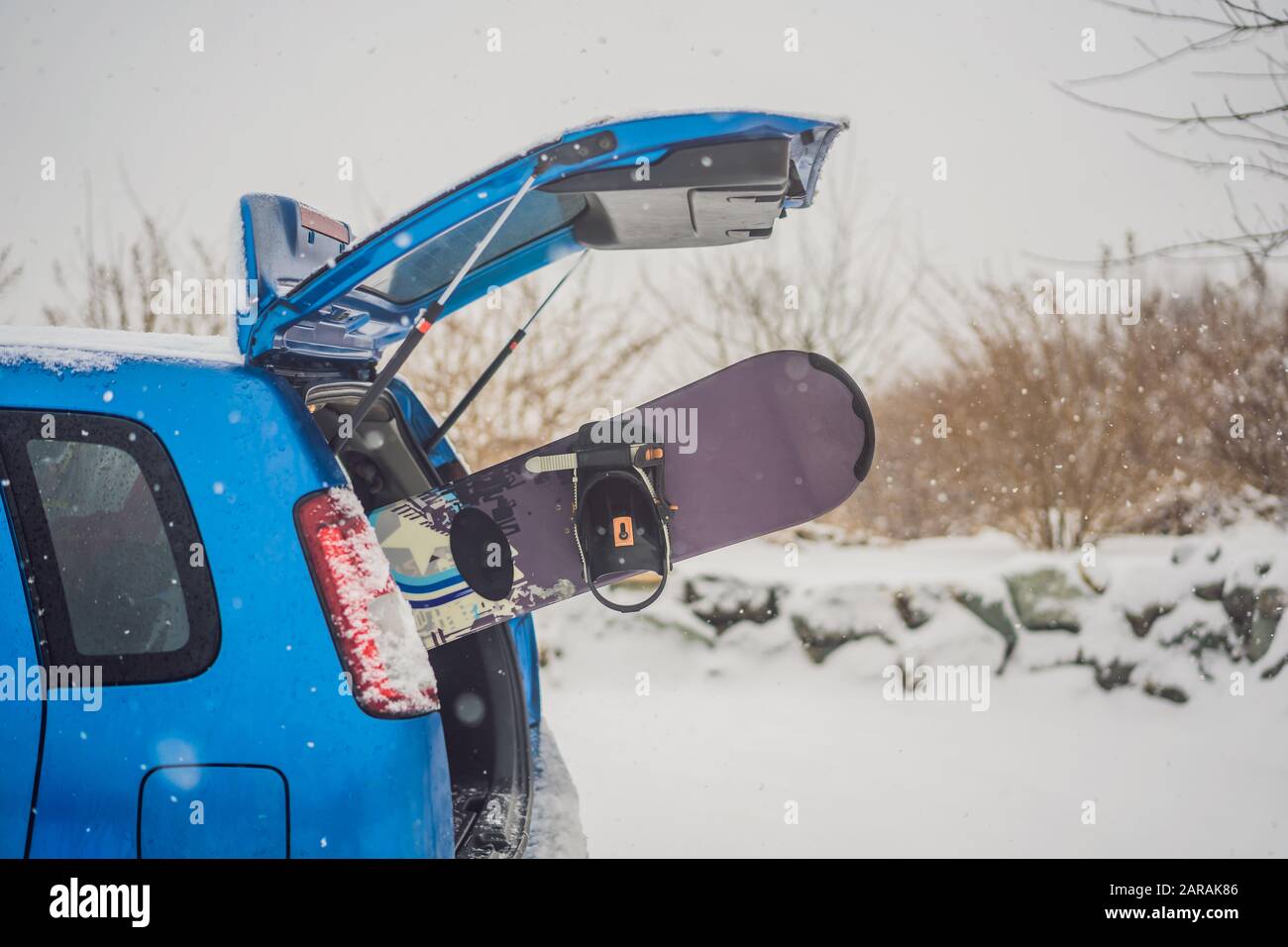 The snowboard does not fit into the car. A snowboarder is trying to