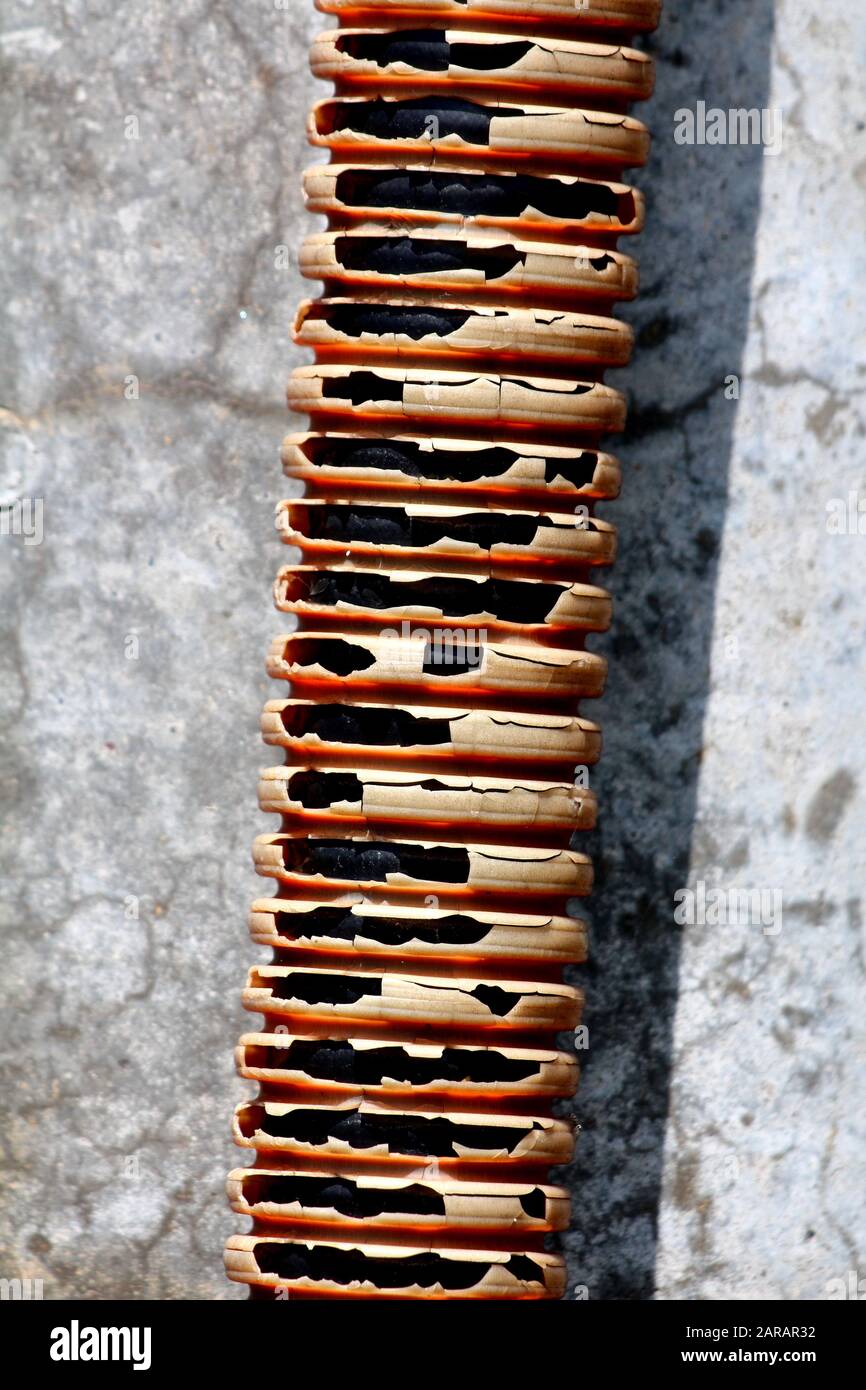 Broken cracked dilapidated old orange corrugated plastic PVC flexible