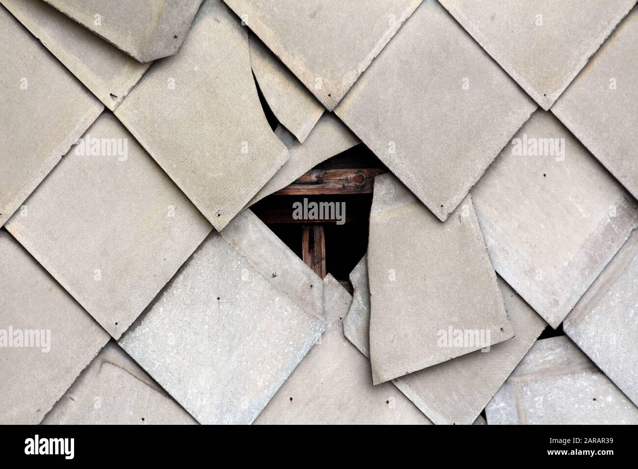Broken destroyed office building wall covered with protective tiles revealing wooden support frame at abandoned industrial complex texture background Stock Photo