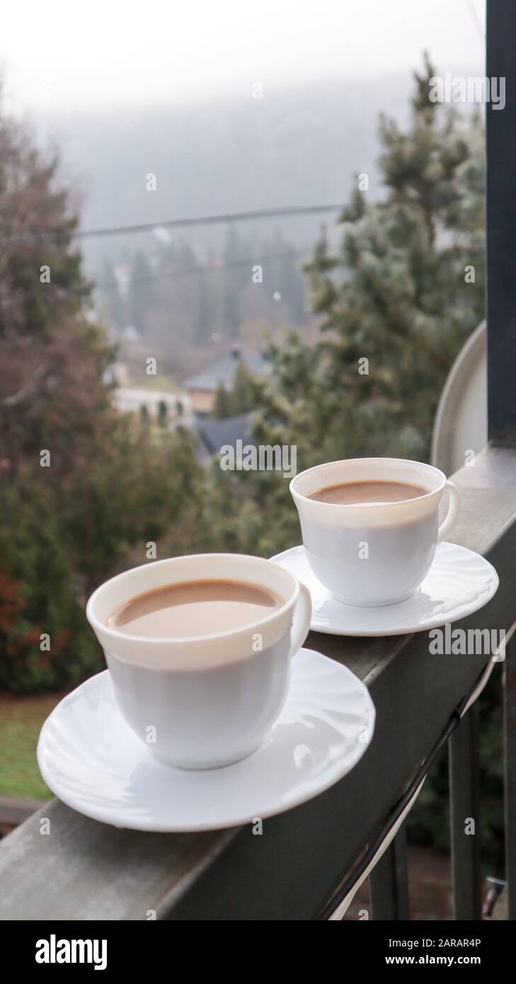 Two coffee cups on a balcony with mountain landscape in the morning. Two  cups of morning coffee, standing on the side of the balcony, with a magical  Stock Photo - Alamy