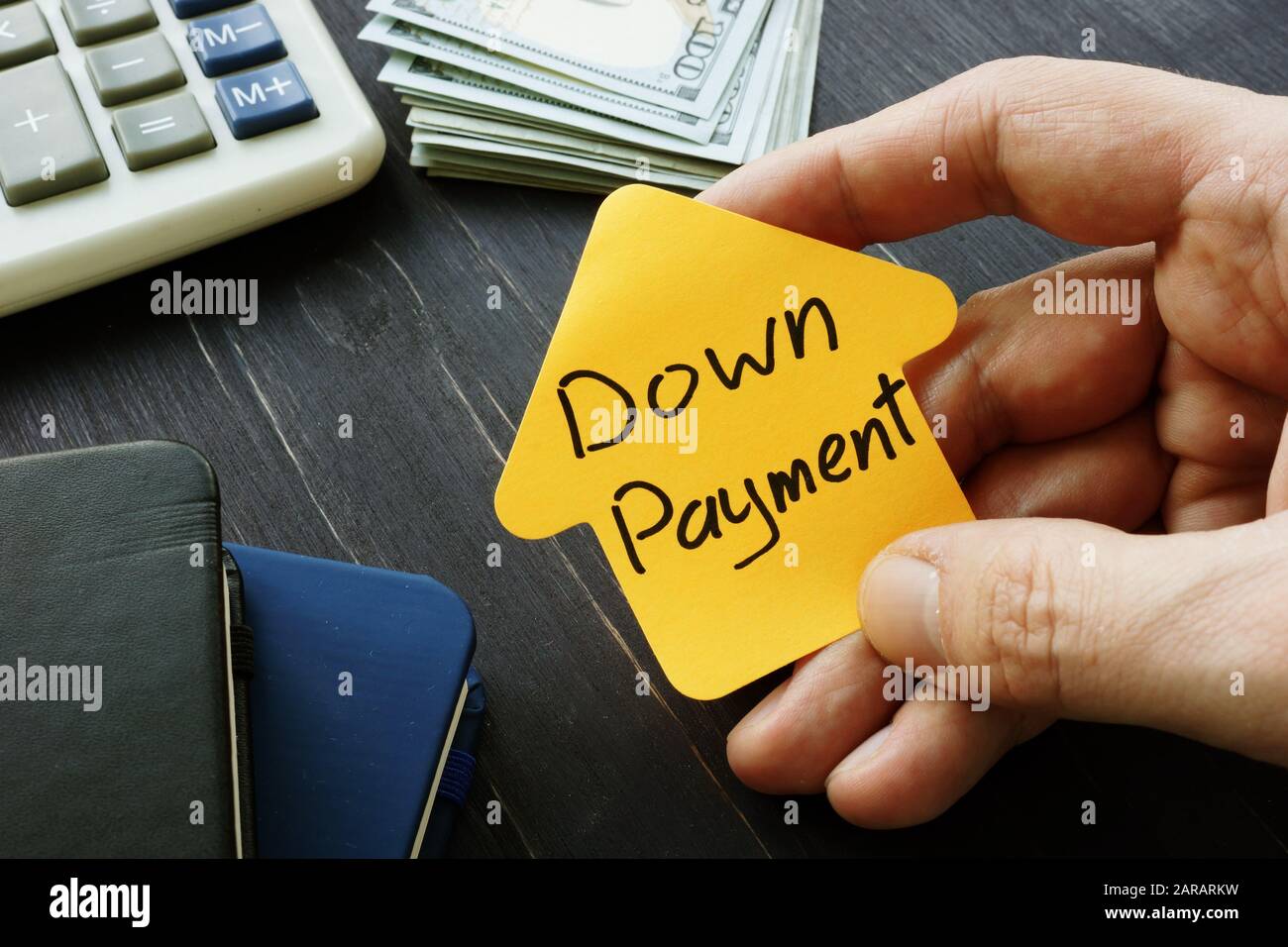 Hand holds Down Payment inscription near desk. Stock Photo