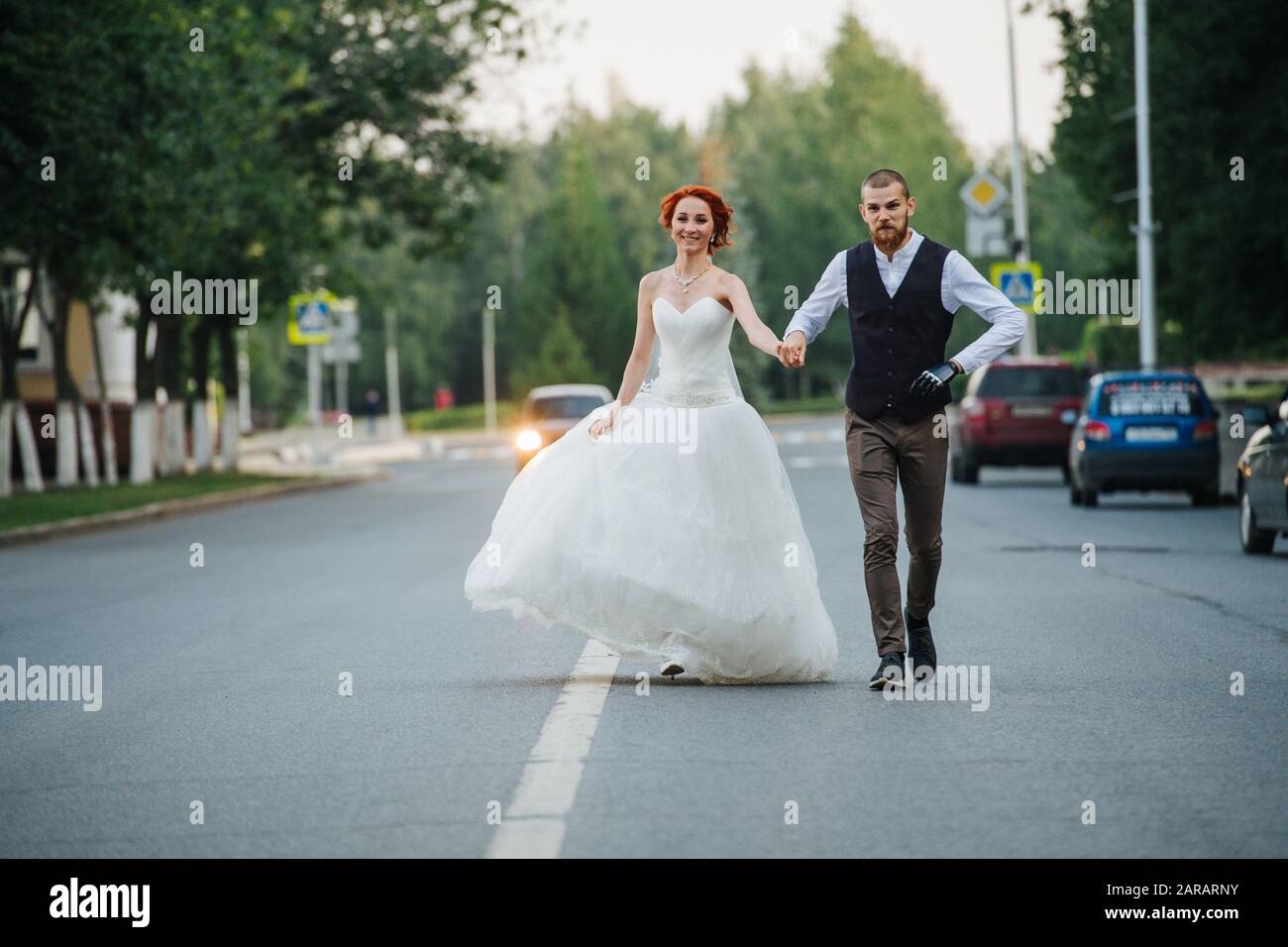 The bride and groom walking together in the middle of a street Stock Photo