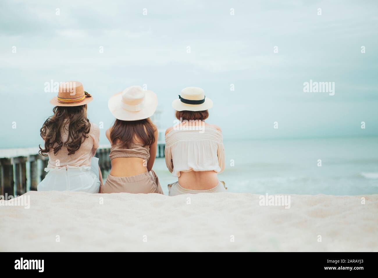 three woman wearing straw hat sitting on vacation sea beach Stock Photo ...