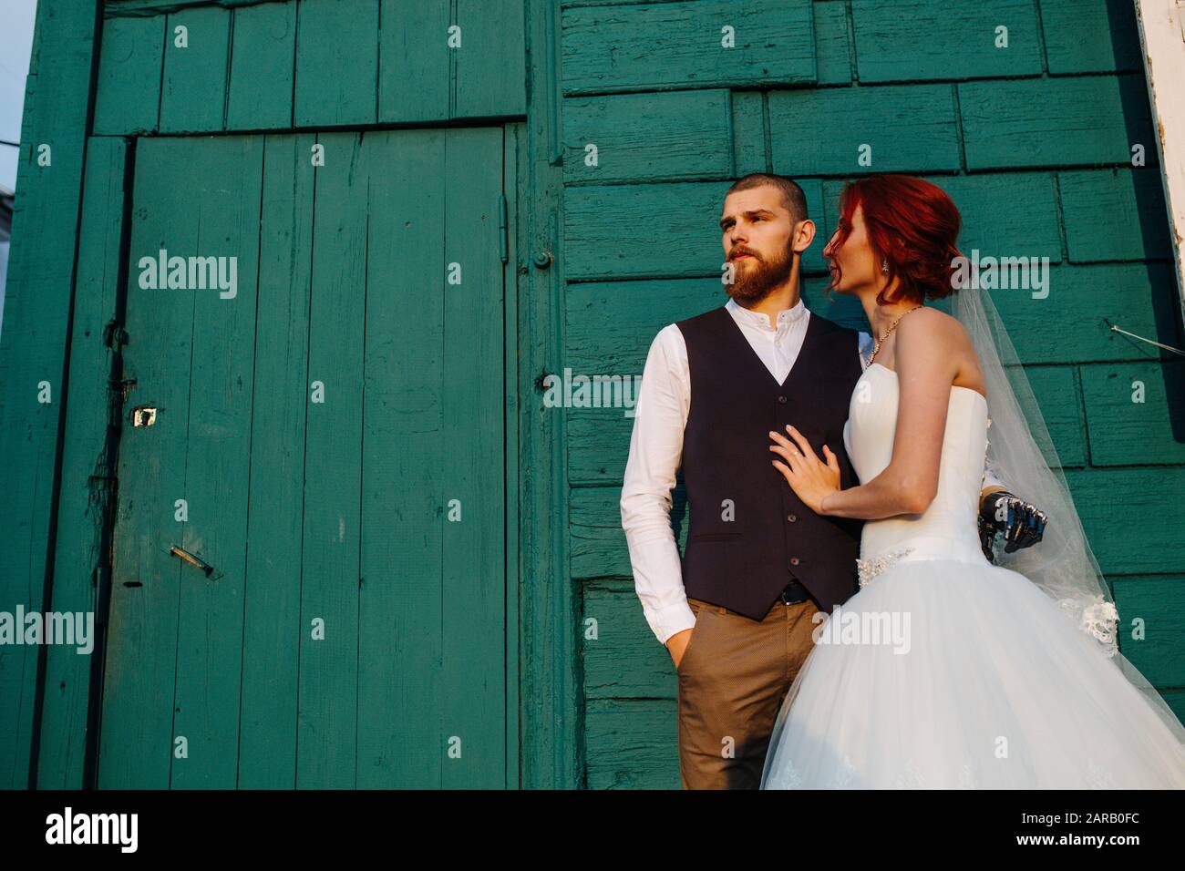 Handsome newly wed man and wife standind in front of painted wall with a door Stock Photo