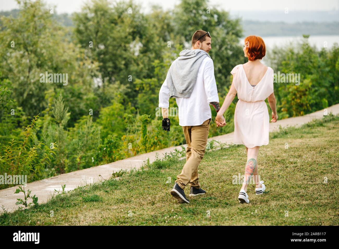 Happy married middle age couple taking a walk through a park hand by hand Stock Photo