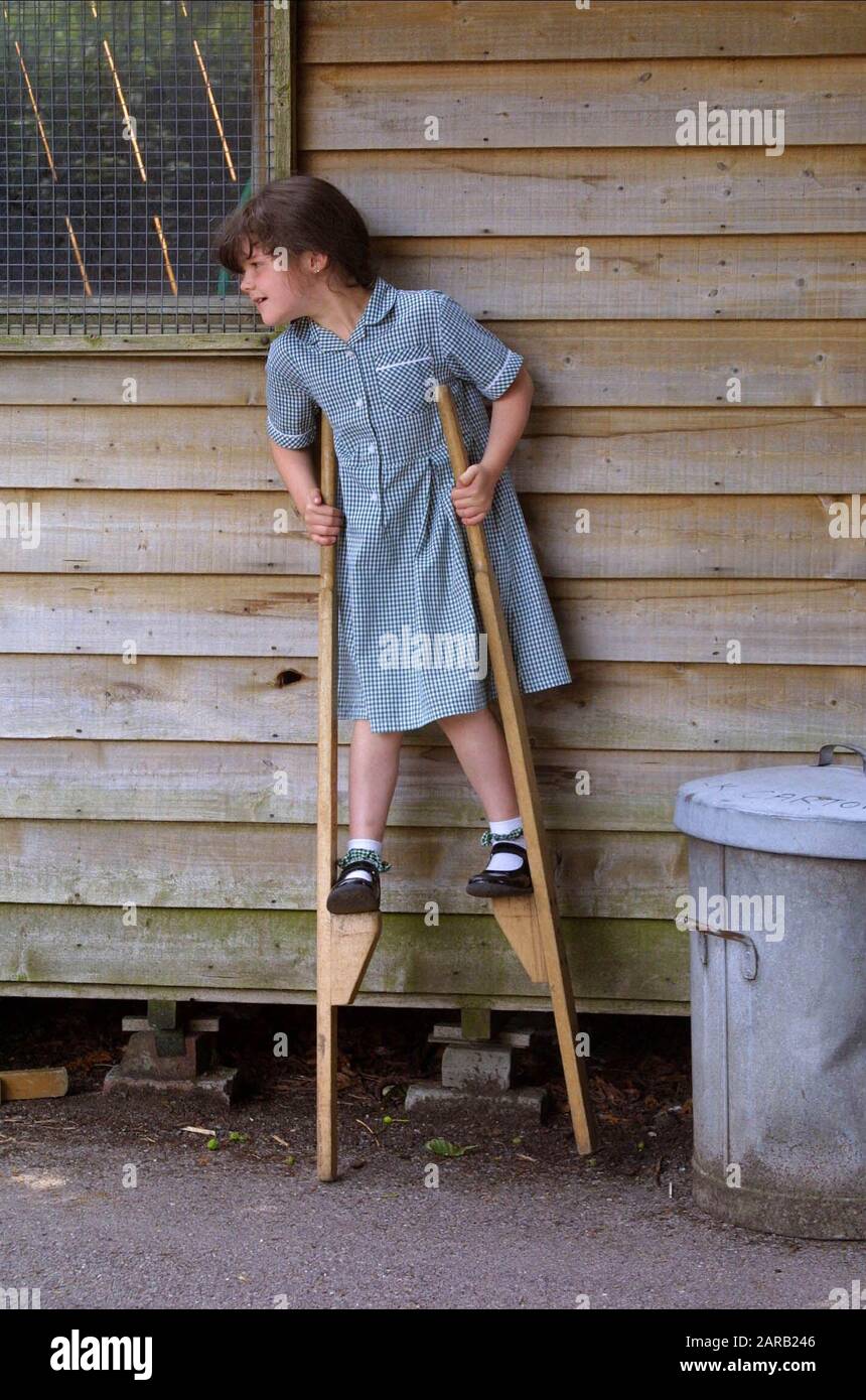 Uniformed young girl playing on stilts in a Primary Village School yard Stock Photo