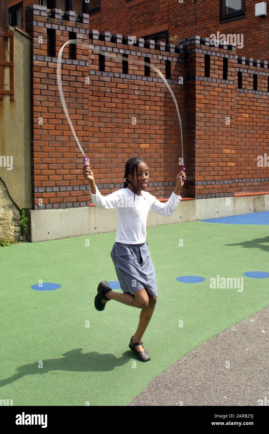 Black girl skipping rope in primary playground Stock Photo
