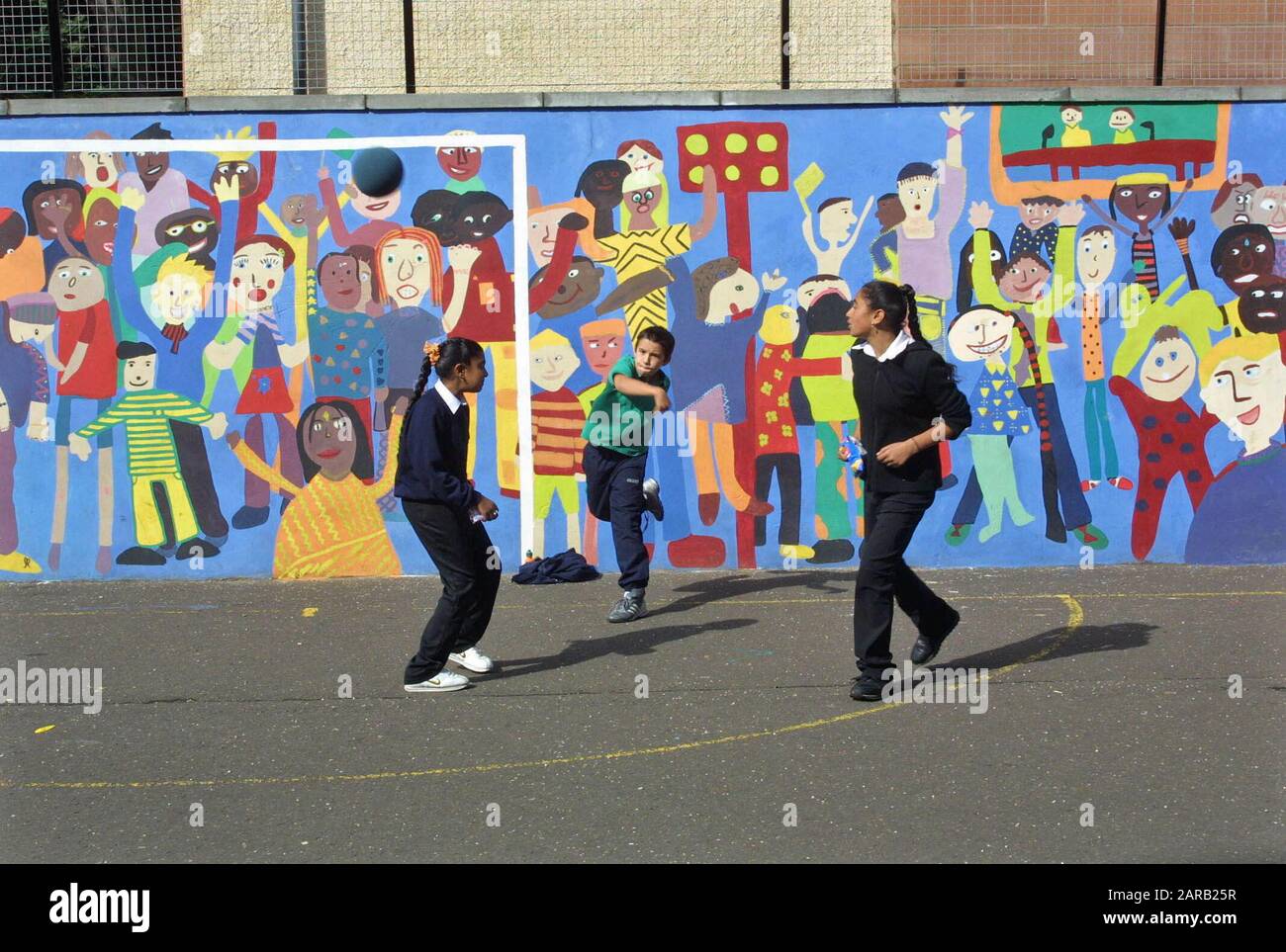 Secondary school playground with bright wall mural painted by the students showing Asian kids in uniform playing Stock Photo