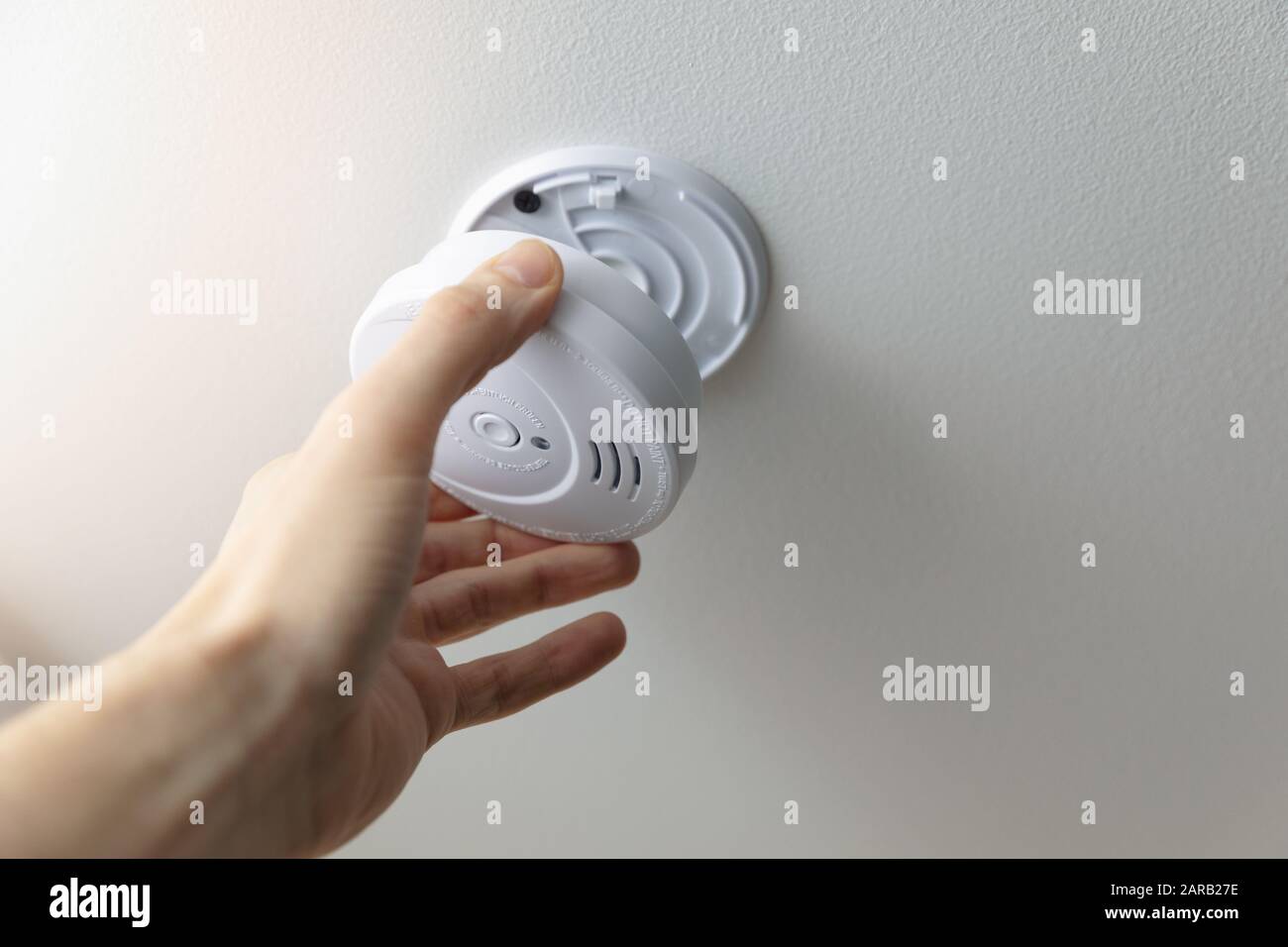 hand installing smoke detector on the room ceiling Stock Photo