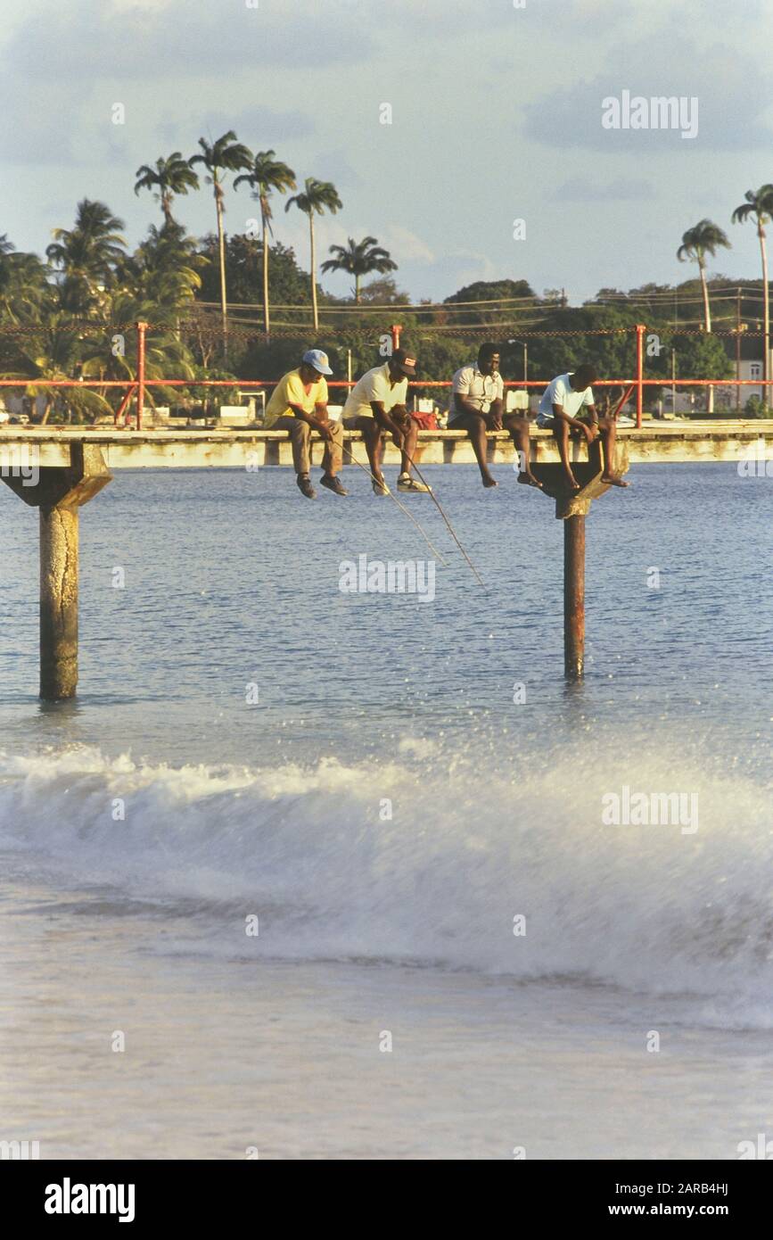 Bajan men fishing from a wooden pier. Barbados. Caribbean. West Indies Stock Photo