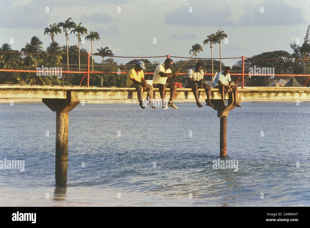 Bajan men fishing from a wooden pier. Barbados. Caribbean. West Indies Stock Photo