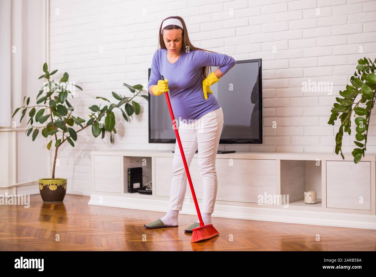 Tired pregnant woman having pain in back while she is cleaning her